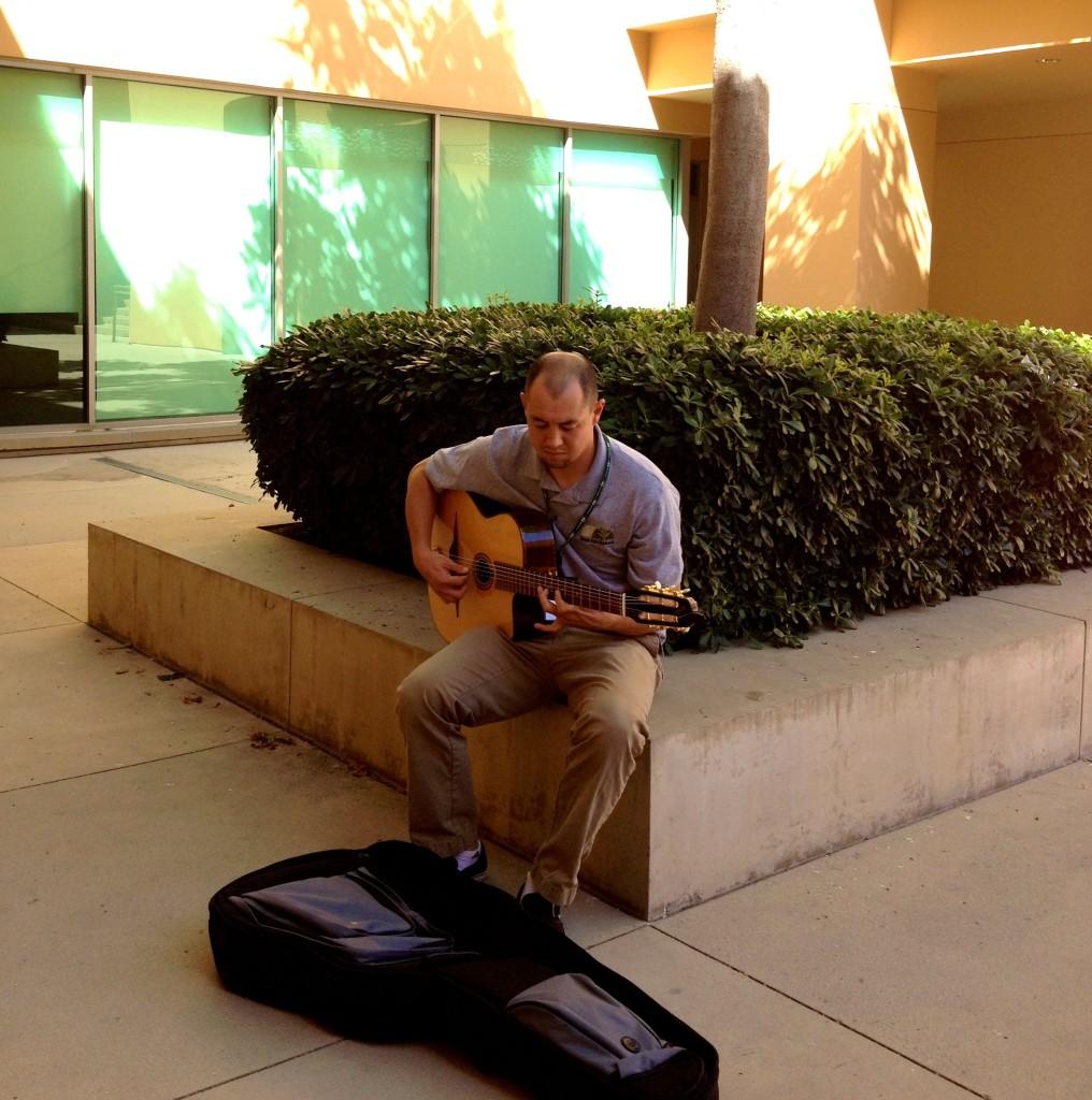 Arts and Sciences teacher Chris Irwin strums his guitar in the D. Diane Anderson Family Humanities Building courtyard. September 19 2013. Photographer: Erika Lynn-Green