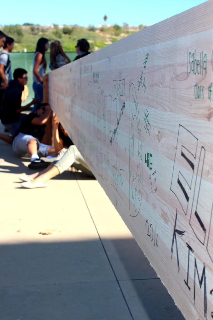 Students and families write on a large wood beam to be used for the new Argyros Family Science Center Wednesday November 13, 2013. Photographer: Kandis McGee 