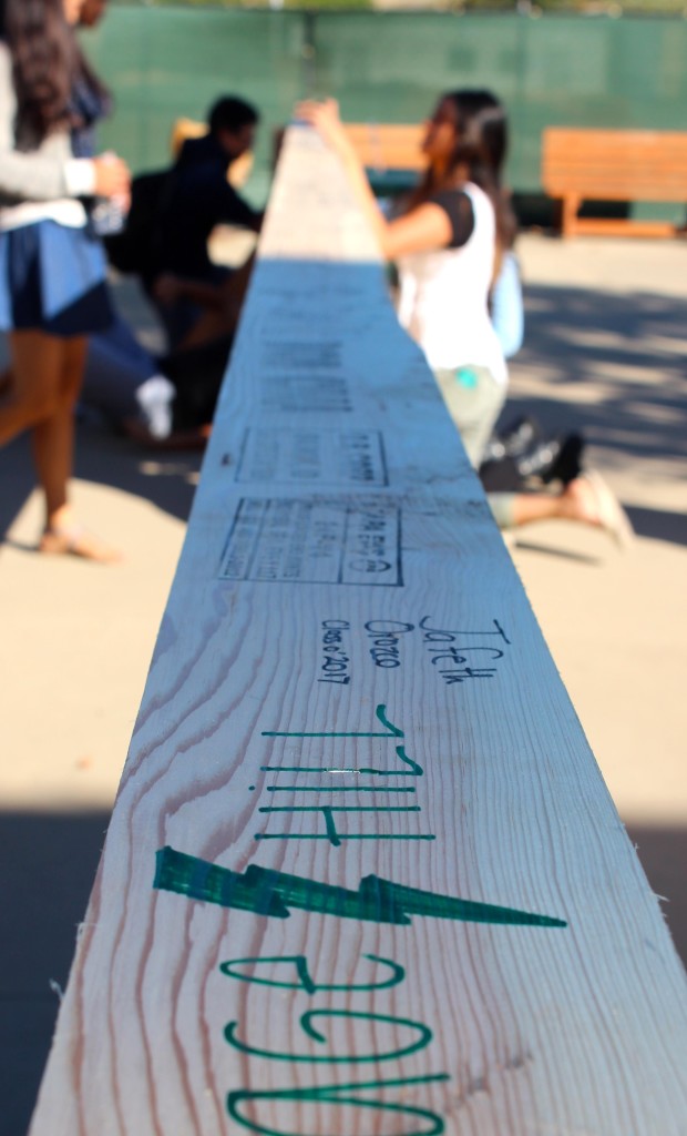 Students and families write on a large wood beam to be used for the new Argyros Family Science Center Wednesday November 13, 2013. Photographer: Kandis Mcgee
