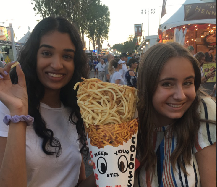 Seniors+Ishani+Patel+and+Miranda+deBruyne+share+some+of+the+famous+OC+Fair+curly+fries