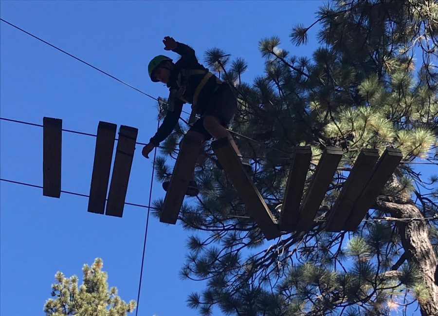 Adam Hayek walks across a suspended ladder on the high ropes course