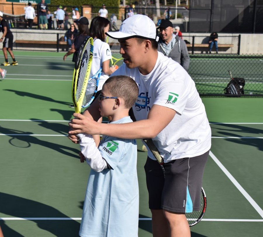 Senior Ryan Ha helps an ACEing Autism participant learn how to hit a solid forehand. 