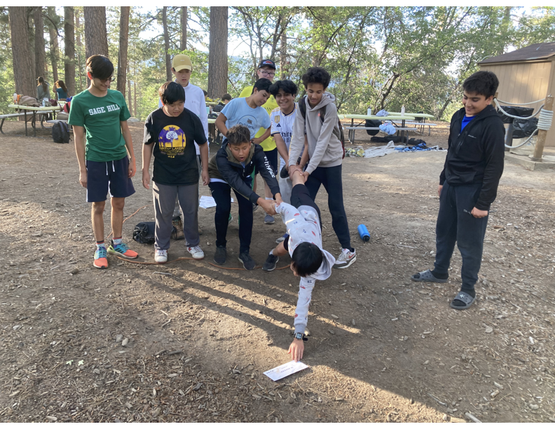 Freshman Eric Zhao attempts to grab an envelope with the help of his Advisory Group during a team-building exercise at Camp Cedar Lake.