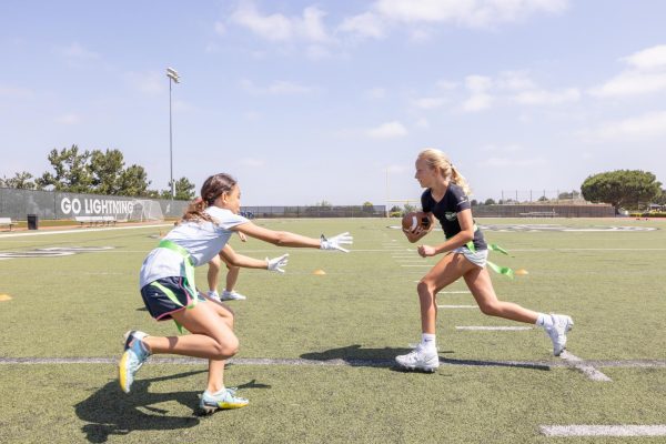 Two middle school girls practice during a Flag Football camp on Ramer Field in July 2023.